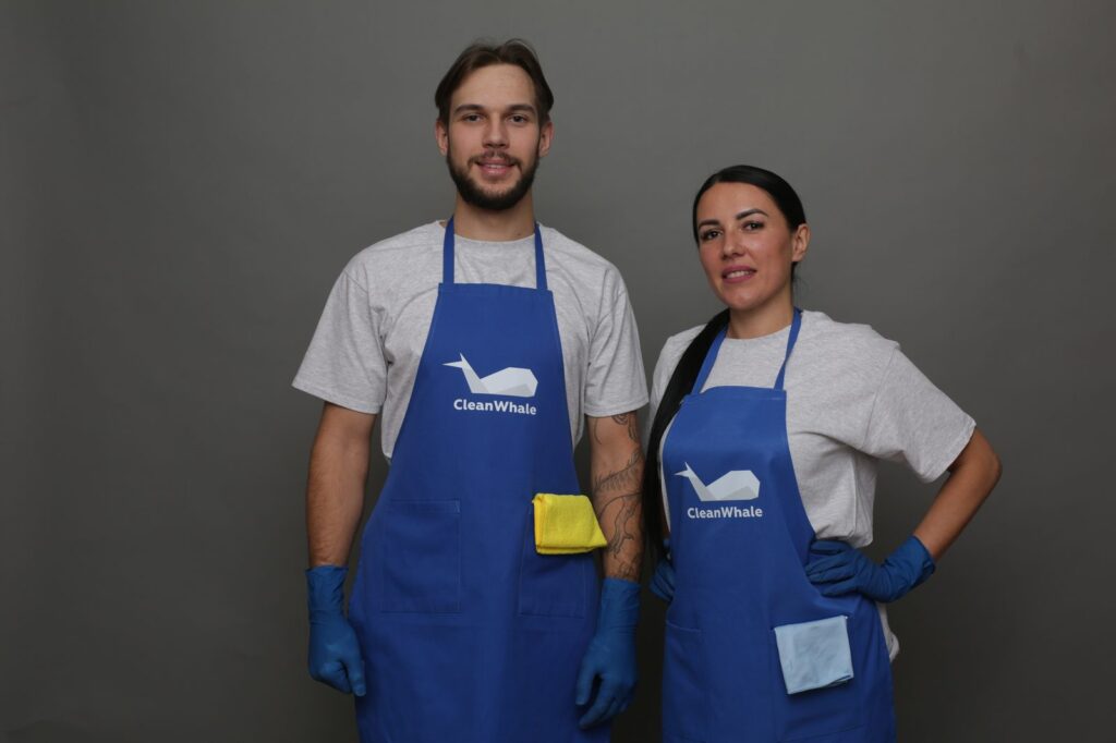 Pracownicy CleanWhale: kobieta i mężczyzna w niebieskich fartuchach na szarym tle.